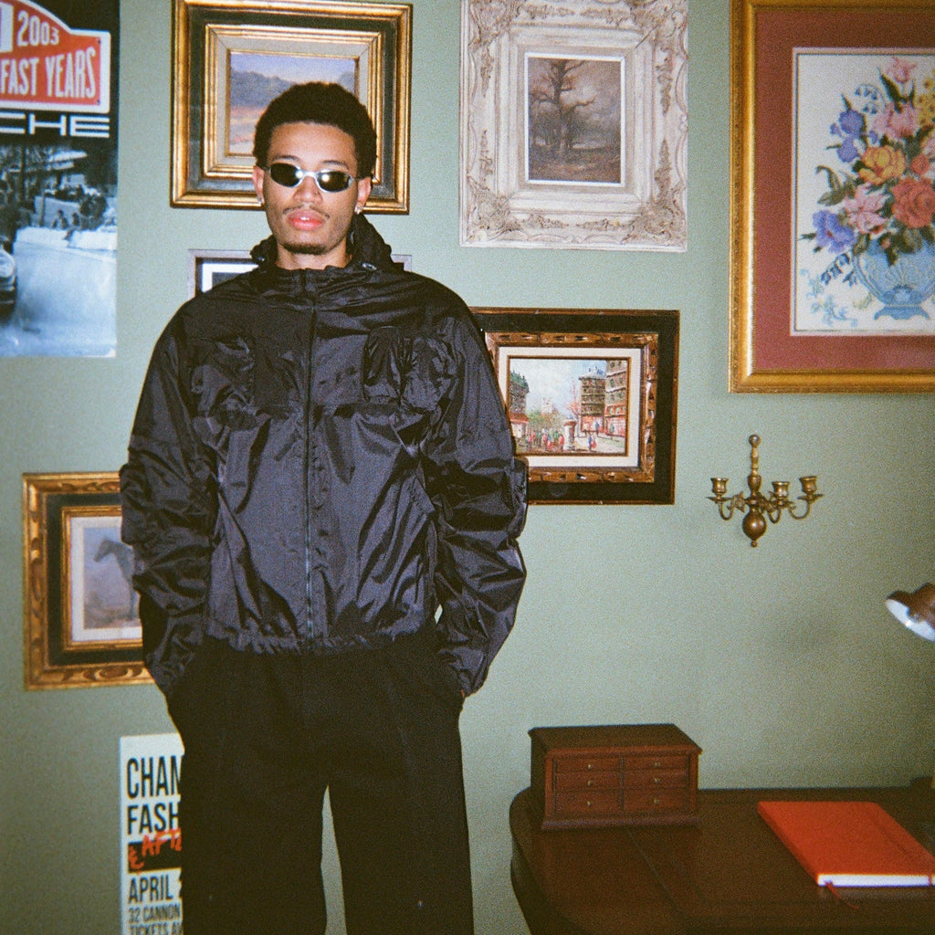 Person wearing a black rain jacket in a room with framed pictures on the wall.